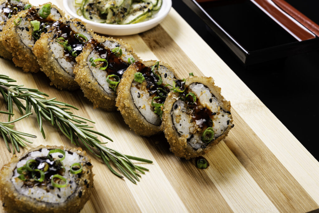 Hot fried Sushi Roll with Salmon and Cheese. Sushi menu. Japanese food On bamboo cutting board to be served.